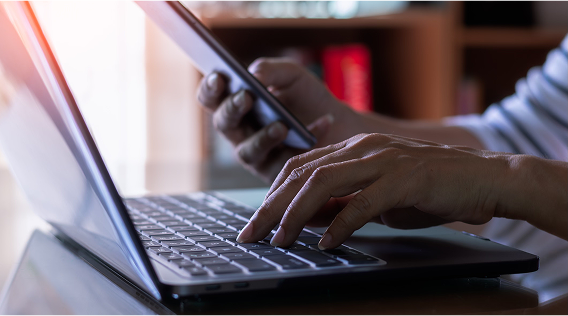 Contractor using laptop to browse KWM Gutterman’s website and a phone to use KWM’s mobile app, available on Apple and Google Play Stores.