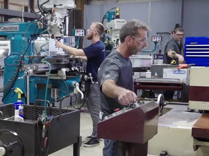 KWM Gutterman technician using a CNC machine to fabricate precision parts for new Ironman gutter machines.